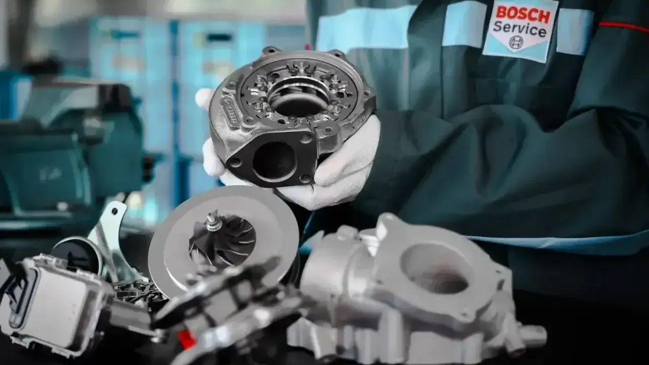 Mechanik w rękawiczkach prezentuje części do regeneracji turbo. W tle logo Bosch Service.