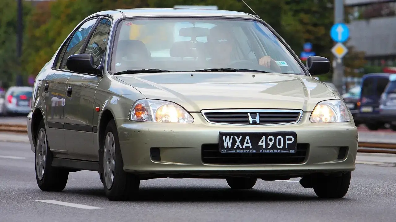 Złoty sedan Honda Civic z widocznym numerem rejestracyjnym WXA 490P. Brak tablicy rejestracyjnej z przodu.