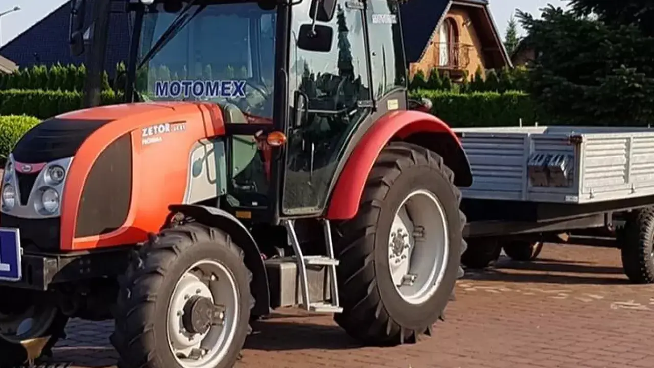 Czerwony Zetor z przyczepą, gotowy do pracy. Marzenie o własnym polu i prawo jazdy na traktor staje się rzeczywistością.