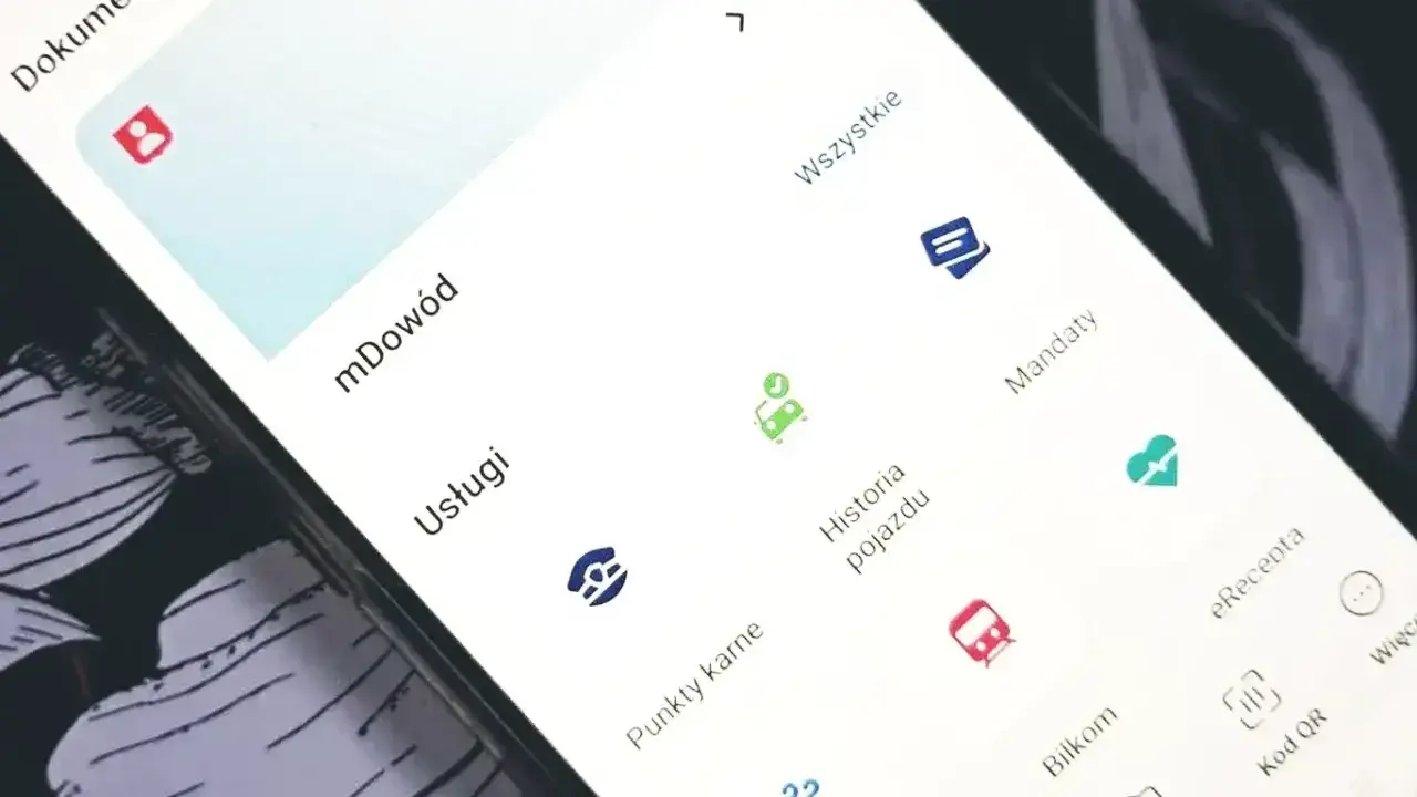 Na ekranie telefonu widać aplikację z opcjami: mDowód, Usługi, Historia pojazdu, Mandaty, eRecepta, Bilkom, Kod QR. Można tu sprawdzić swoje punkty karne.