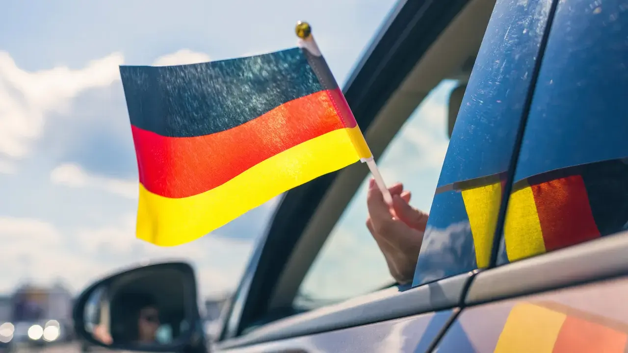 Niemiecka flaga powiewa z okna samochodu. To jak raport TUV z podróży, pełen dumy i radości.