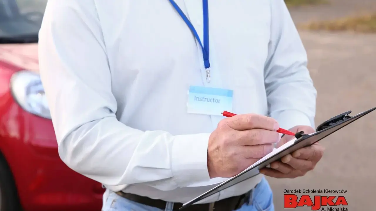 Instruktor notuje dopuszczalne błędy na egzaminie praktycznym na prawo jazdy. Obok czerwony samochód.