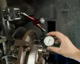 Mechanik mierzy bicie tarczy hamulcowej, by zdiagnozować drgania kierownicy przy hamowaniu.