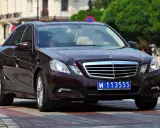 Ciemnobrązowy Mercedes z tablicami dyplomatycznymi W 113555, jadący po ulicy.