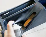 Ręka trzyma puszkę z farbą w sprayu, malowanie elementu konsoli środkowej samochodu.