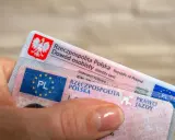 Dłoń trzyma polski dowód osobisty i prawo jazdy. Dokumenty te mogą być przydatne, gdy planujesz podróż do USA i chcesz mieć pewność, że Twoje polskie prawo jazdy jest uznawane.