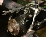 Mechanik dokręca śruby przy piaście, wymieniając łożysko w samochodzie.