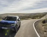 Niebieski SUV jedzie krętą drogą przez pustynny krajobraz. Pomyśl o ubezpieczeniu auta za granicą, by podróżować bez obaw.
