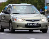 Złoty sedan Honda Civic z widocznym numerem rejestracyjnym WXA 490P. Brak tablicy rejestracyjnej z przodu.