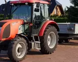 Czerwony Zetor z przyczepą, gotowy do pracy. Marzenie o własnym polu i prawo jazdy na traktor staje się rzeczywistością.