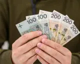Dłonie trzymają polskie banknoty: 100 i 200 zł. Może to być zwrot OC dla niepełnosprawnych lub po prostu wypłata.