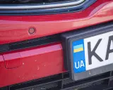 Czerwony zderzak z czujnikiem parkowania i tablicą rejestracyjną UA.