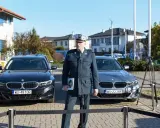 Funkcjonariusz w mundurze stoi między dwoma nieoznakowanymi radiowozami BMW.