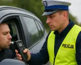 Policjant bada trzeźwość kierowcy alkomatem. Powyżej 0,5 promila jaka kara grozi za jazdę pod wpływem alkoholu.