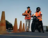 Instruktorka motocyklowa obserwuje kursanta podczas ćwiczeń na placu. Zastanawiasz się, ile godzin jazdy na kat. A potrzeba, by zdać egzamin?