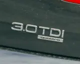 Emblemat "3.0 TDI quattro" na ciemnym lakierze samochodu. Informuje o pojemności silnika 3.0 litra i napędzie quattro.