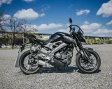 Czarny motocykl Yamaha, idealny na pierwsze prawo jazdy a1, stoi na żwirowym placu przed budynkiem.