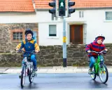 Dwóch chłopców na rowerach czeka na zielone światło. Czy karta rowerowa jest obowiązkowa? Bezpieczeństwo przede wszystkim!