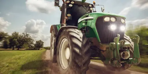 Zielony traktor pędzi po polnej drodze, gotowy do pracy. To maszyna rolnicza, której zakup jest ważną umową kupna sprzedaży.