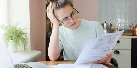 Zmartwiona kobieta analizuje dokumenty, szukając informacji o zwrocie OC po sprzedaży samochodu.