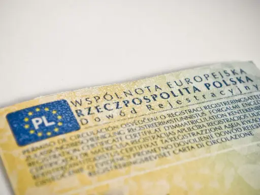 Dowód rejestracyjny pojazdu, niezbędny do ubezpieczenia samochodu, z flagą PL i tekstem w wielu językach.