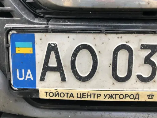 Ukraińskie tablice rejestracyjne z flagą i literami "UA" na białym tle. Widoczne cyfry "AO 037".