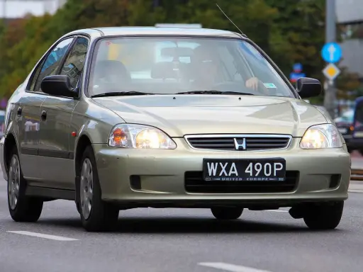 Złoty sedan Honda Civic z widocznym numerem rejestracyjnym WXA 490P. Brak tablicy rejestracyjnej z przodu.