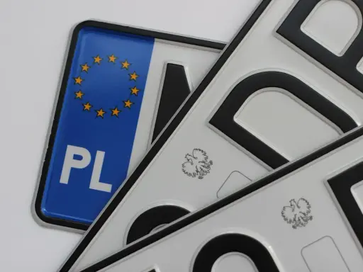 Kilka małych tablic rejestracyjnych, jedna z symbolem Unii Europejskiej i napisem PL, pozostałe z godłem Polski.