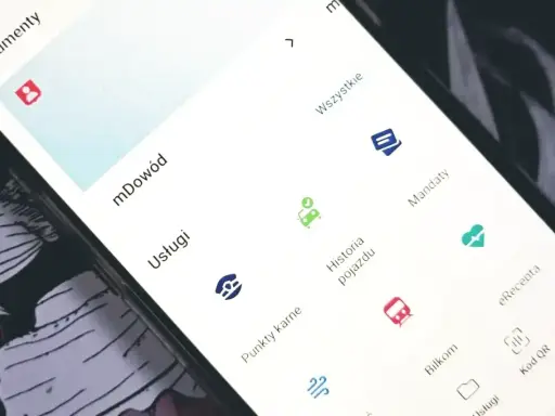 Na ekranie telefonu widać aplikację z opcjami: mDowód, Usługi, Historia pojazdu, Mandaty, eRecepta, Bilkom, Kod QR. Można tu sprawdzić swoje punkty karne.