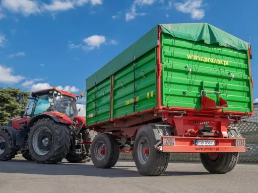 Czerwony traktor z zieloną przyczepą. Dowiedz się, jakich przyczep nie trzeba rejestrować, by swobodnie poruszać się po drogach.