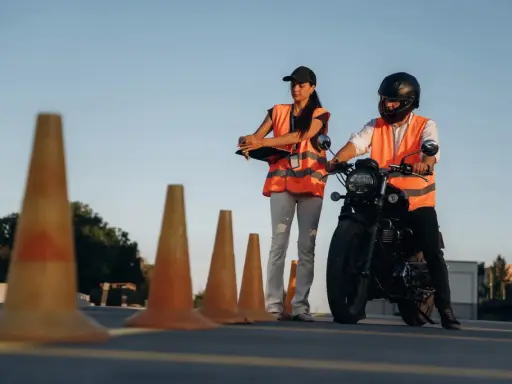 Instruktorka motocyklowa obserwuje kursanta podczas ćwiczeń na placu. Zastanawiasz się, ile godzin jazdy na kat. A potrzeba, by zdać egzamin?