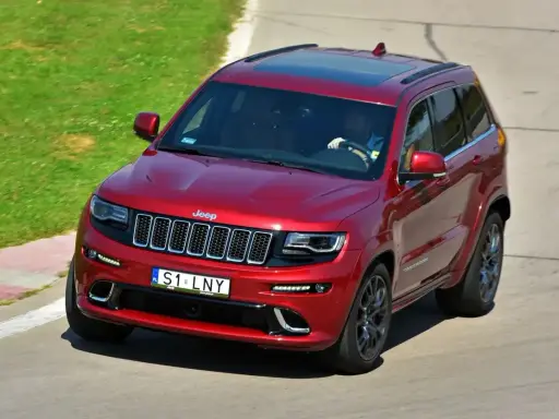 Czerwony Jeep Grand Cherokee z indywidualną tablicą rejestracyjną "S1 LNY" na torze wyścigowym.