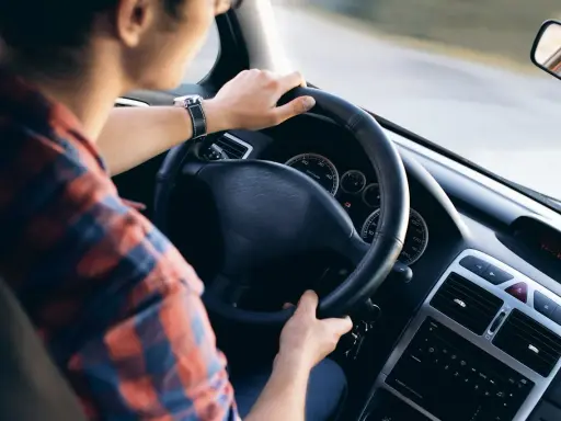 Mężczyzna w kratę prowadzi auto, kluczyki wiszą przy kierownicy. Czy AC przechodzi na nowego właściciela?