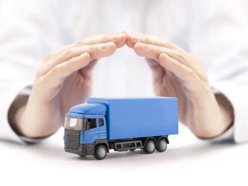 Ręce chronią niebieską ciężarówkę, symbolizując ubezpieczenie AC w kosztach transportu.