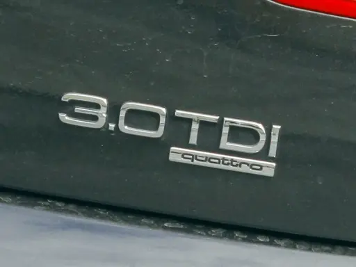 Emblemat "3.0 TDI quattro" na ciemnym lakierze samochodu. Informuje o pojemności silnika 3.0 litra i napędzie quattro.