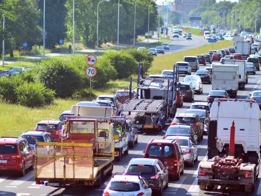 Korek na drodze, sznur samochodów i ciężarówek. Widać znak ograniczenia prędkości do 70. Może to być sytuacja wymagająca polisa car.