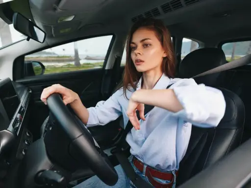 Kobieta za kierownicą zastanawia się, czy OC przedłuża się automatycznie. Widok na morze i palmy.