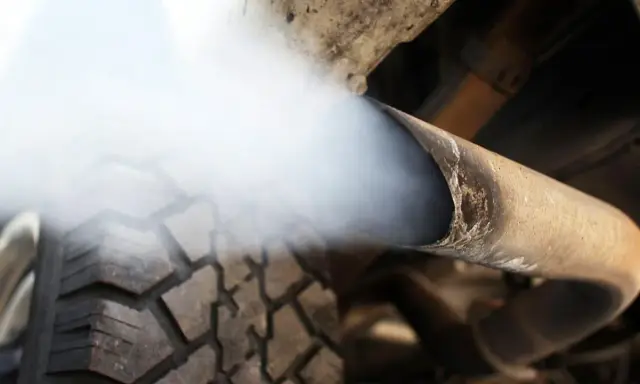Biały dym z wydechu diesel wydobywa się z rury, zasłaniając fragment opony.