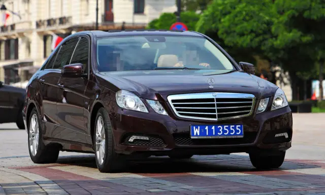 Ciemnobrązowy Mercedes z tablicami dyplomatycznymi W 113555, jadący po ulicy.