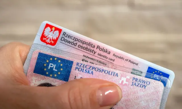 Dłoń trzyma polski dowód osobisty i prawo jazdy. Dokumenty te mogą być przydatne, gdy planujesz podróż do USA i chcesz mieć pewność, że Twoje polskie prawo jazdy jest uznawane.
