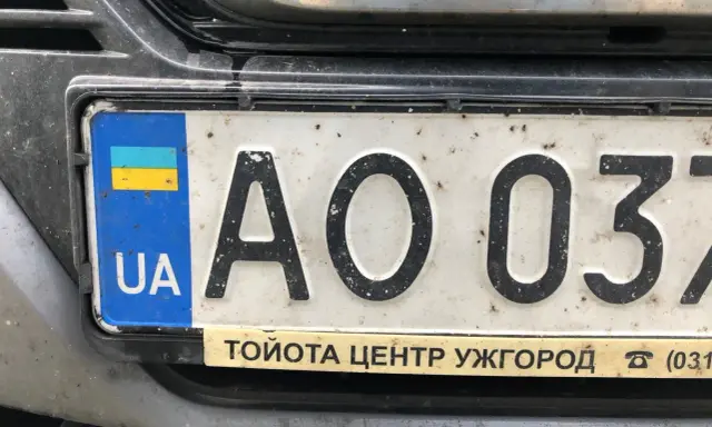 Ukraińskie tablice rejestracyjne z flagą i literami "UA" na białym tle. Widoczne cyfry "AO 037".