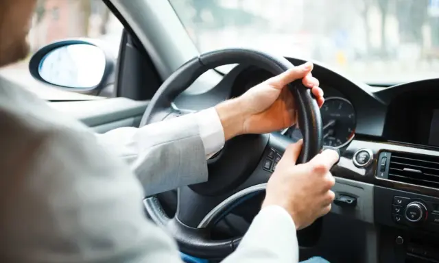 Mężczyzna za kierownicą zastanawia się, czy autocasco warto. Bezpieczeństwo na drodze to podstawa.
