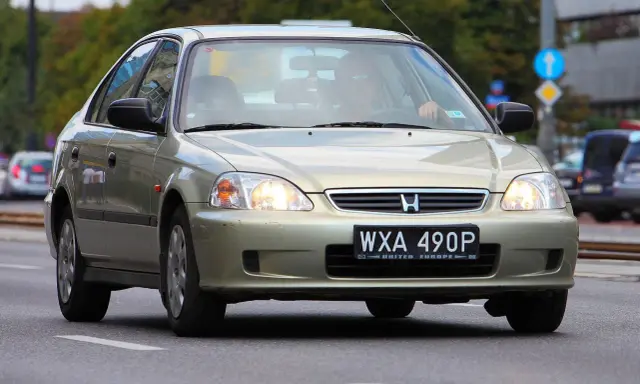 Złoty sedan Honda Civic z widocznym numerem rejestracyjnym WXA 490P. Brak tablicy rejestracyjnej z przodu.