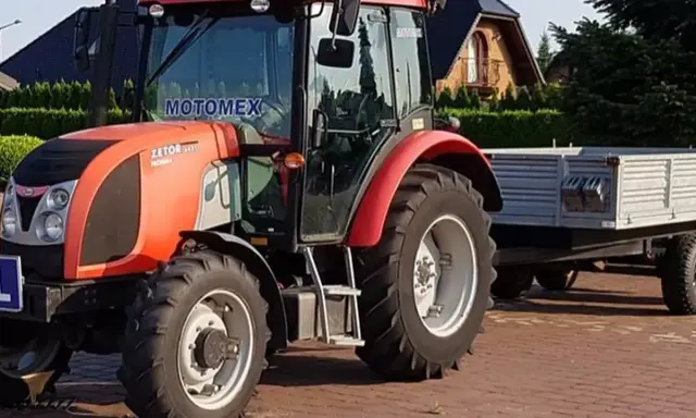 Czerwony Zetor z przyczepą, gotowy do pracy. Marzenie o własnym polu i prawo jazdy na traktor staje się rzeczywistością.