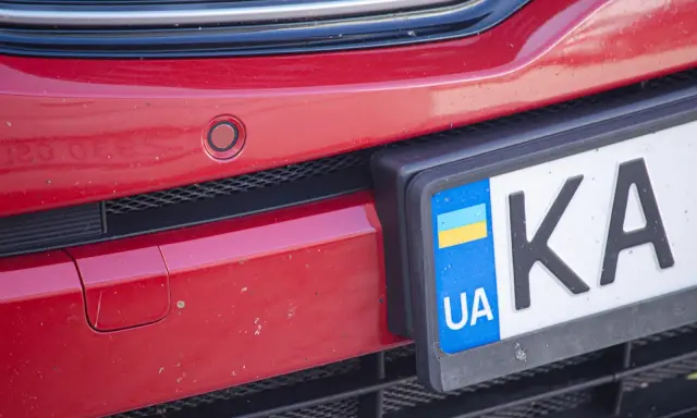 Czerwony zderzak z czujnikiem parkowania i tablicą rejestracyjną UA.