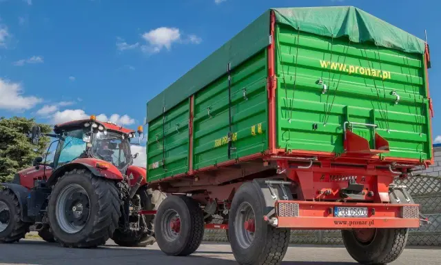 Czerwony traktor z zieloną przyczepą. Dowiedz się, jakich przyczep nie trzeba rejestrować, by swobodnie poruszać się po drogach.