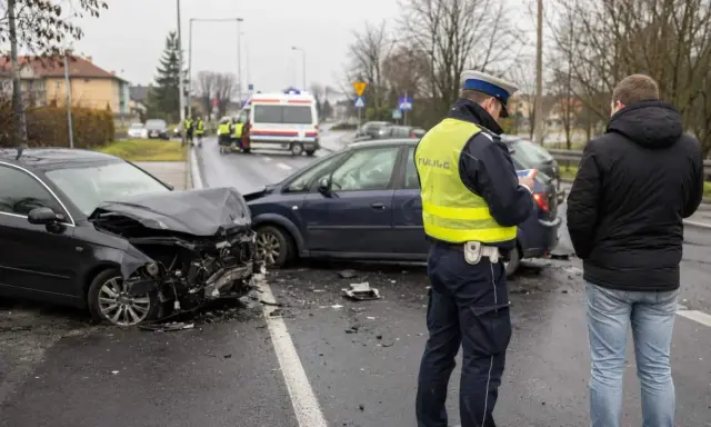 Policjant spisuje sprawcę wypadku. Zniszczone auta i karetka na sygnale świadczą o tym, że doszło do tragedii, być może przez jazdę pod wpływem.