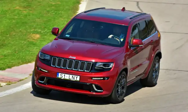 Czerwony Jeep Grand Cherokee z indywidualną tablicą rejestracyjną "S1 LNY" na torze wyścigowym.