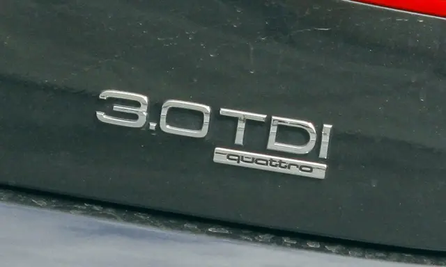 Emblemat "3.0 TDI quattro" na ciemnym lakierze samochodu. Informuje o pojemności silnika 3.0 litra i napędzie quattro.