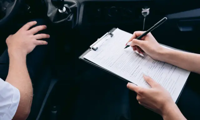 Kobieta wypełnia formularz podczas rejestracji samochodu przez dealera.
